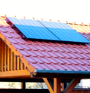 Solaranlage auf einem roten Ziegeldach eines Holzgebäudes.