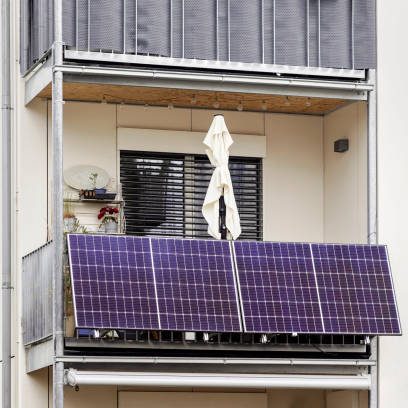 Ein Balkon mit Solarpanelen und einem Wäschegestell im Hintergrund.