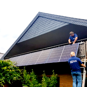 Zwei Männer installieren Solarpanels auf einem Dach.